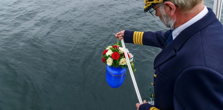 Beisetzung einer Urne während der Seebestattung mit Adler-Schiffe
