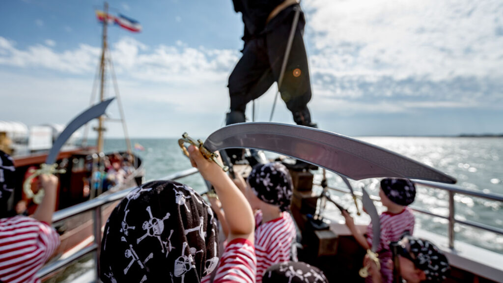 Kinder bestehen mit Säbeln Piratenmutproben an Bord einer Piratenfahrt