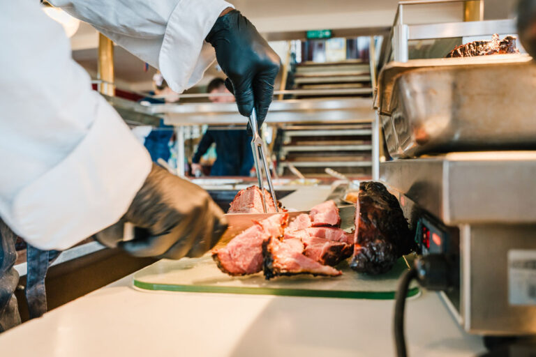 Koch schneidet Braten am warmen Buffet der Freya auf